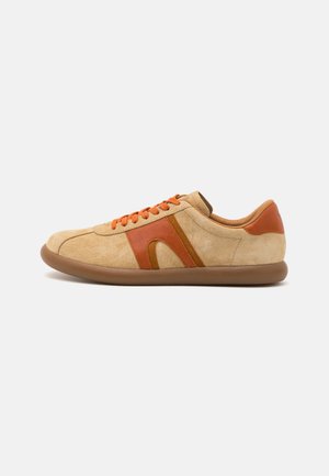 Beige Veloursleder-Sneaker mit orangen Akzenten, abgerundeter Zehenpartie, kontrastierenden Streifen und orangenen Schnürsenkeln. Die gummierte Sohle sorgt für Grip.