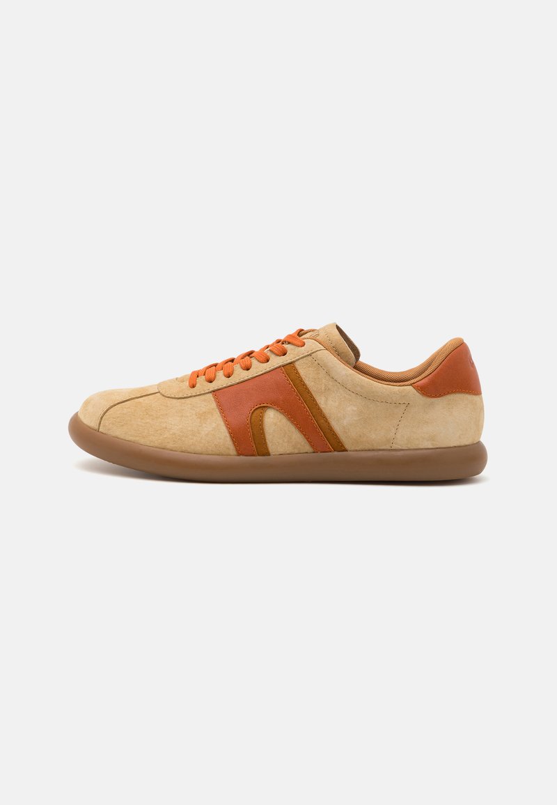 Sneaker beige in suede con accenti arancioni, caratterizzato da una punta rotonda, strisce a contrasto e lacci arancioni. La suola in gomma offre aderenza.