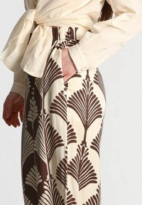 Pantaloni marroni e crema con un motivo a foglia, caratterizzati da un fit rilassato, tasca laterale e chiusura con bottone in vita.