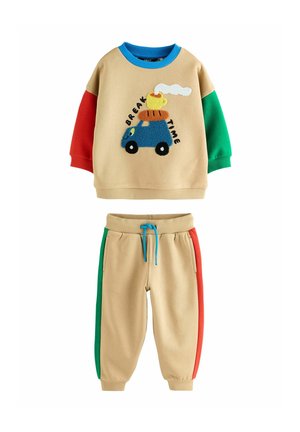 Completo beige a due pezzi composto da una felpa a maniche lunghe con accenti blu, rossi e verdi, e pantaloni beige abbinati con strisce laterali multicolori.