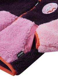 Fleece jacket featuring purple, pink, and orange fabric sections. Notable details include a Moomin logo patch and soft, textured surfaces.