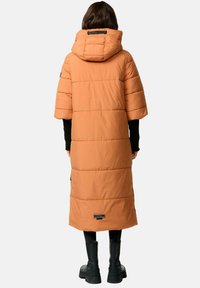 Lange, gewatteerde jas in verbrande sinaasappel met een capuchon, korte mouwen en zwarte accenten. Voorzien van horizontale stiksels en een logo patch.