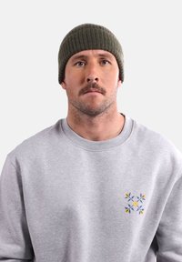 Bonnet côtelé vert et sweat-shirt gris avec un motif floral brodé en jaune et bleu, col rond et coupe décontractée.