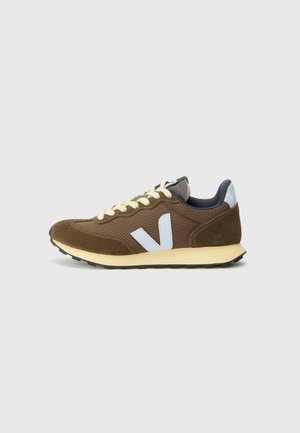Brown suede and mesh sneaker with light blue accents, yellow laces, textured surface, and black rubber sole. Minimalist design.
