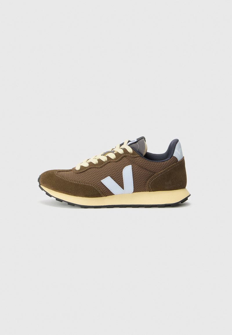 Brown suede and mesh sneaker with light blue accents, yellow laces, textured surface, and black rubber sole. Minimalist design.