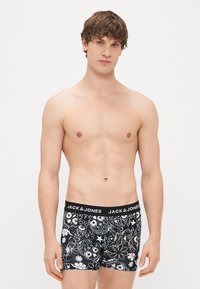Svart boksershorts med blomstermønster og hvite design, med en svart midjebånd som har "JACK & JONES" i hvit tekst.