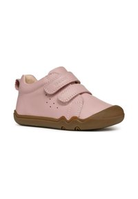 Chaussure en cuir rose clair avec deux bandes Velcro, semelle en caoutchouc marron, bout arrondi et petites perforations sur le côté pour la respirabilité.