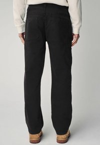Pantalons cargo noirs avec une coupe décontractée, dotés de deux poches arrière et d'une poche latérale. Fabriqués en tissu durable, avec une texture lisse.