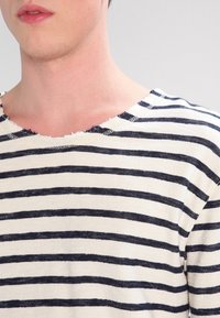 Pasiasta koszula z długim rękawem, w niebiesko-białe poziome paski, z brzegiem wykończonym na surowo i miękką teksturą.