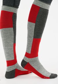 Kniestrümpfe in Rot, Grau und Schwarz mit einem geometrischen Farbblockdesign. Hergestellt aus weichem, strukturiertem Stoff mit gerippten Akzenten.