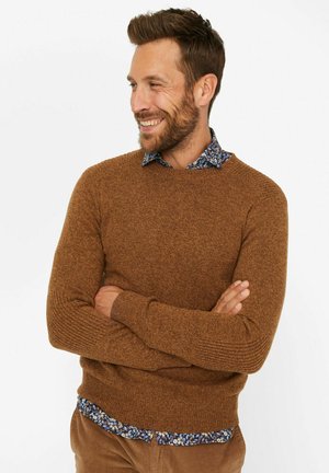 Brown textured sweater with a crew neckline, paired with a blue floral button-up shirt that peeks from underneath.