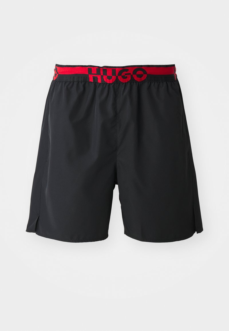 Zwarte zwempakshorts van lichtgewicht stof, met een rode elastische tailleband met het "HUGO" logo, zijsplitten voor extra bewegingsvrijheid.