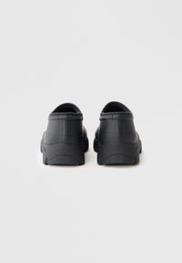 Black rubber clogs featuring a rounded toe, thick sole, and backless design. Smooth texture with subtle grooves for grip.