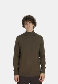 Maglione a collo alto in maglia marrone con polsi e orlo a costine, caratterizzato da un sottile dettaglio del logo sul petto e un design aderente.