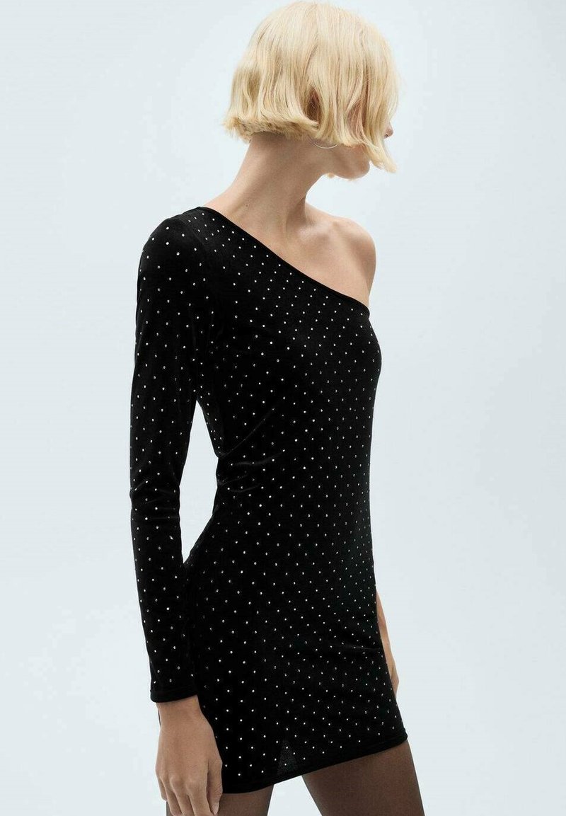 Rochie din catifea neagră, cu un singur umăr, prezintă broderii cu puncte argintii, mânecă lungă pe o parte și o silueta ajustată.