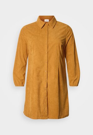 Obleka srajce iz manšestrastega blaga v gorčično rumeni barvi z dolgimi rokavi, gumbi spredaj, ovratnikom in pliseiranim dizajnom. Mehka tekstura in sproščen kroj.