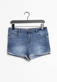 Keskitummansiniset farkkushortsit, joissa haalistettu pesu. Varustettu viidellä taskulla, käärittyillä lahkeensuilla ja metallisella nappikiinnityksellä. Kiinnitetty mustaan vaatetelineeseen.