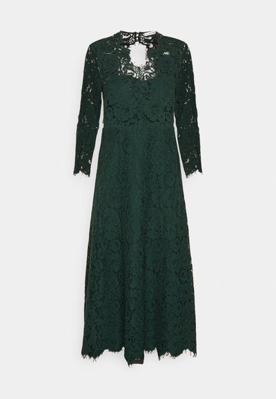 Σκοτεινό πράσινο δαντελένιο φόρεμα με μακριά μανίκια, με ψηλό λαιμό και λεπτομέρεια με κλειδαρότρυπα, που καταλήγει σε ένα τελείωμα με κυματιστό άκρο.