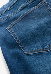 Donkerblauwe spijkerbroek van denim met een achterzak, zichtbare oranje stiksels en een lichte textuur. De stof lijkt duurzaam en soepel.