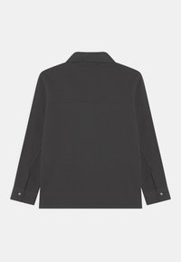 Sort skjorte med lange ærmer og krave, med lige kant og knapper ved manchetterne. Lavet af blødt, tekstureret stof.