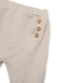 Pantalones de tela acanalada beige con una textura suave, cinturilla elástica y tres botones de madera en el bolsillo lateral para un cierre fácil.