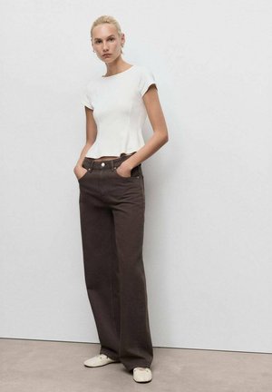 Weißes Baumwoll-Oberteil mit kurzen Ärmeln, figurbetont an der Brust, mit einem peplum Saum; kombiniert mit hochtaillierten, dunkelbraunen, weiten Hosen. Leichte Schuhe.