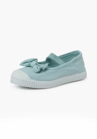 Zapatilla de lona azul claro con puntera de goma blanca y suela texturizada, que presenta un lazo en la correa superior y un diseño plano.