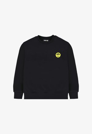 Felpa nera a maniche lunghe con scollo a girocollo e una piccola faccina gialla sorridente con zanne da vampiro sul petto a sinistra.