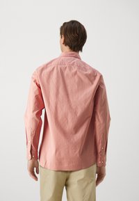 Camicia a maniche lunghe color rosa chiaro in cotone, con colletto a punta e polsini abbottonati. La vista posteriore mostra un tessuto liscio e strutturato.