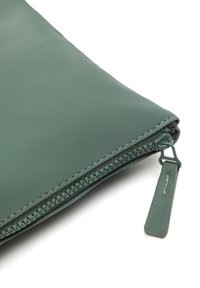 Zelená taška na zips vyrobená z textúrovaného materiálu, s kontrastným zipsom a malým držadlom s jemnými švy.