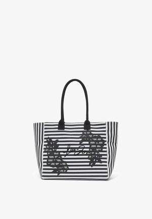 Sac fourre-tout à rayures noires et blanches avec poignées noires, appliques de dentelle florale et logo en écriture cursive au centre avant.