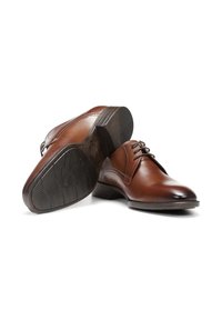 Zapatos de vestir de cuero marrón con un acabado liso, punta redondeada, diseño de cordones y suela de goma texturizada, expuestos en un ángulo.