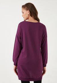 Maglietta a maniche lunghe, pullover, di colore viola. Presenta una vestibilità comoda, un ampio scollo e polsini a coste con una superficie liscia. Design semplice, senza fantasie.