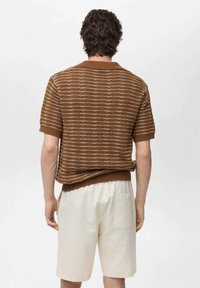 Brun strikket polo-shirt med korte ærmer, der har et struktureret design og krave. Sammen med lyse shorts.