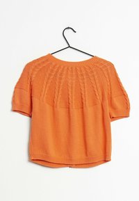 Top lavorato a maglia arancione con maniche corte, caratterizzato da un motivo a trecce attorno al collo e una texture liscia e morbida.