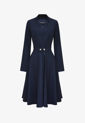 Granatowa sukienka z długim rękawem, dopasowaną talią, rozszerzaną spódnicą, dekoltem w serek, frontowym zamkiem błyskawicznym i ozdobnymi podwójnymi srebrnymi guzikami na pasku.