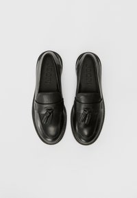Mocassins en cuir noir avec des accents de gland, texture lisse, bout arrondi, semelle intérieure rembourrée et intérieur de marque.