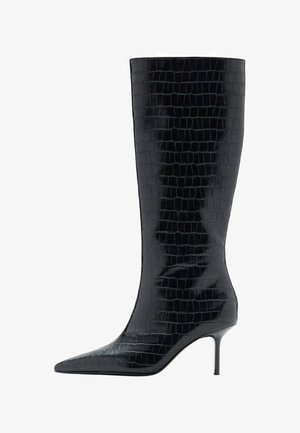 Bota negra hasta la rodilla con tacón de aguja, punta afilada, textura brillante de cocodrilo y silueta elegante. Cuenta con un tacón alto y delgado.