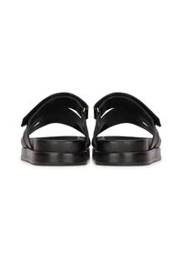 Sandales noires avec deux larges sangles, une semelle plate et une finition texturée. Présente un design minimaliste et des accents en métal doré.