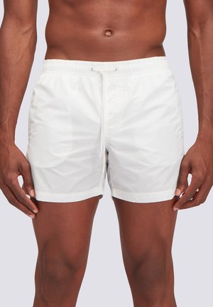 Shorts da bagno bianchi in tessuto leggero e liscio, con elastico in vita e cordino. Presentano un design semplice e una lunghezza fino al ginocchio.