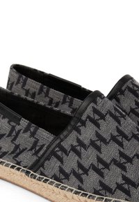 Juodos ir pilkos raštuotos kanvos espadrilės su juodais odiniais akcentais ir jūroje virvės padu, turinčios žemą dizainą patogiam avėjimui.