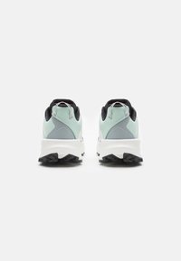 Des chaussures de sport bleu clair et grises avec une semelle blanche, présentant un dessus texturé et des accents noirs, montrant une vue arrière avec des détails de logo.