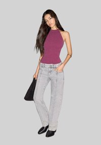 Bordový priliehavý top bez rukávov, svetlošedé vysoké džínsy s vertikálnym šitím a čierne špicaté členkové topánky.