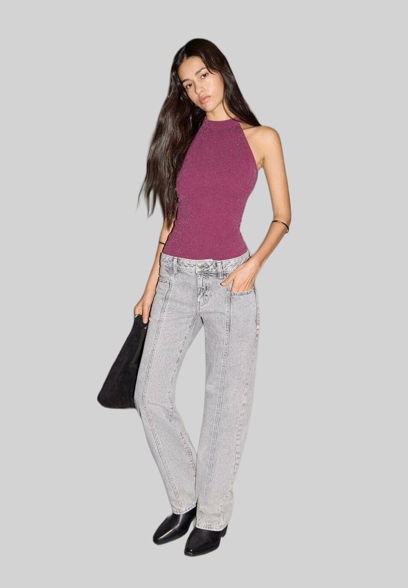 Bordový priliehavý top bez rukávov, svetlošedé vysoké džínsy s vertikálnym šitím a čierne špicaté členkové topánky.