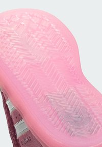 Rubber shoe sole with a translucent pink finish, featuring a zigzag tread pattern. The side shows a burgundy upper and white stripes.