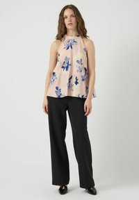 Top halter floreale di un delicato rosa chiaro con fiori blu, abbinato a pantaloni larghi neri. Tessuto morbido, vestibilità comoda, design semplice.