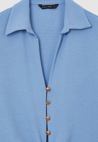 Camicia button-up di colore azzurro chiaro con colletto, dotata di cinque bottoni in legno lungo la parte frontale. Texture liscia, design semplice.
