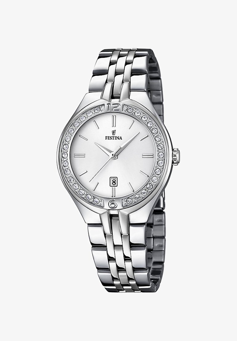 Sidabrinis metalinis laikrodis ant riešo su blizgiu rėmeliu, baltu ciferblatu, numeriais 12 ir 6, datų rodmeniu ir kristaliniais akcentais aplink ciferblatą.