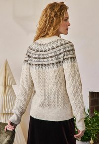 Krém színű kötött pulóver, texturált kábelmintával, szürke és barna mintás nyakkal. Ráncolt mandzsetták és alsó szegély zárják le a megjelenést.