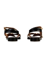 Sandales en cuir noir avec des sangles courbées, semelle beige et accents en or ; semelle plate avec des détails de tread minimal.